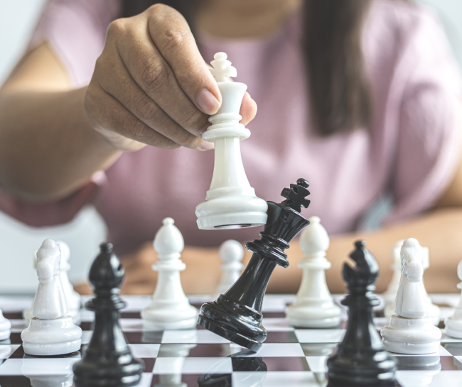 Una persona muove un pezzo degli scacchi: la regina bianca abbatte il re nero su una scacchiera
