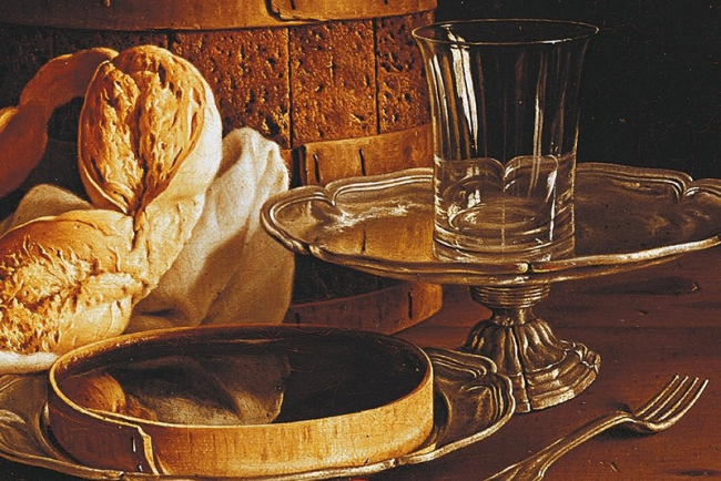 Un dipinto a olio in stile natura morta che raffigura pane, un bicchiere di vetro su alzata argentata, una forchetta e una scatola di legno su un tavolo scuro.