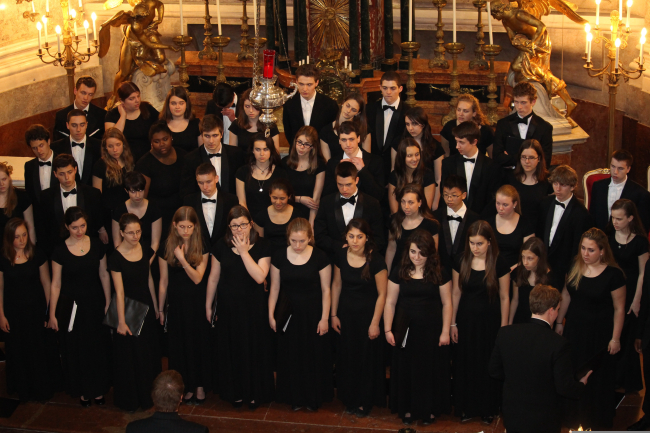 Un coro di giovani in abiti da concerto neri è riunito in una chiesa.