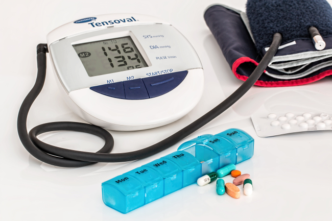 Misuratore di pressione digitale (146/134 mmHg), bracciale, porta-pillole settimanale con farmaci vari e un blister di pastiglie. 