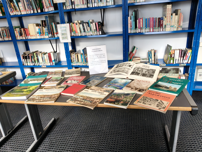 Un tavolo allestito presso la Biblioteca Gallino espone una selezione di libri, guide e volumi illustrati dedicati a Sampierdarena e ad altri territori entrati a far parte della Grande Genova nel 1926
